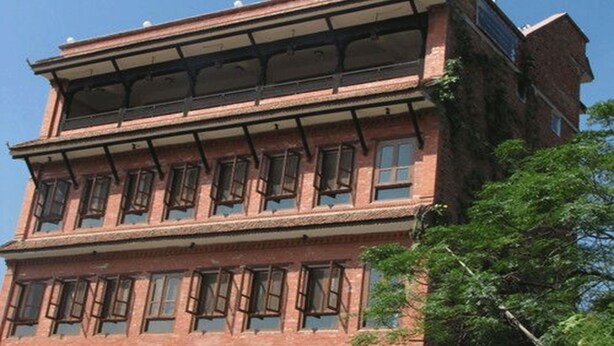 A multi-story brick building with large windows and a balcony on the upper floor. - Heart of Bhaktapur (Bhaktapur)