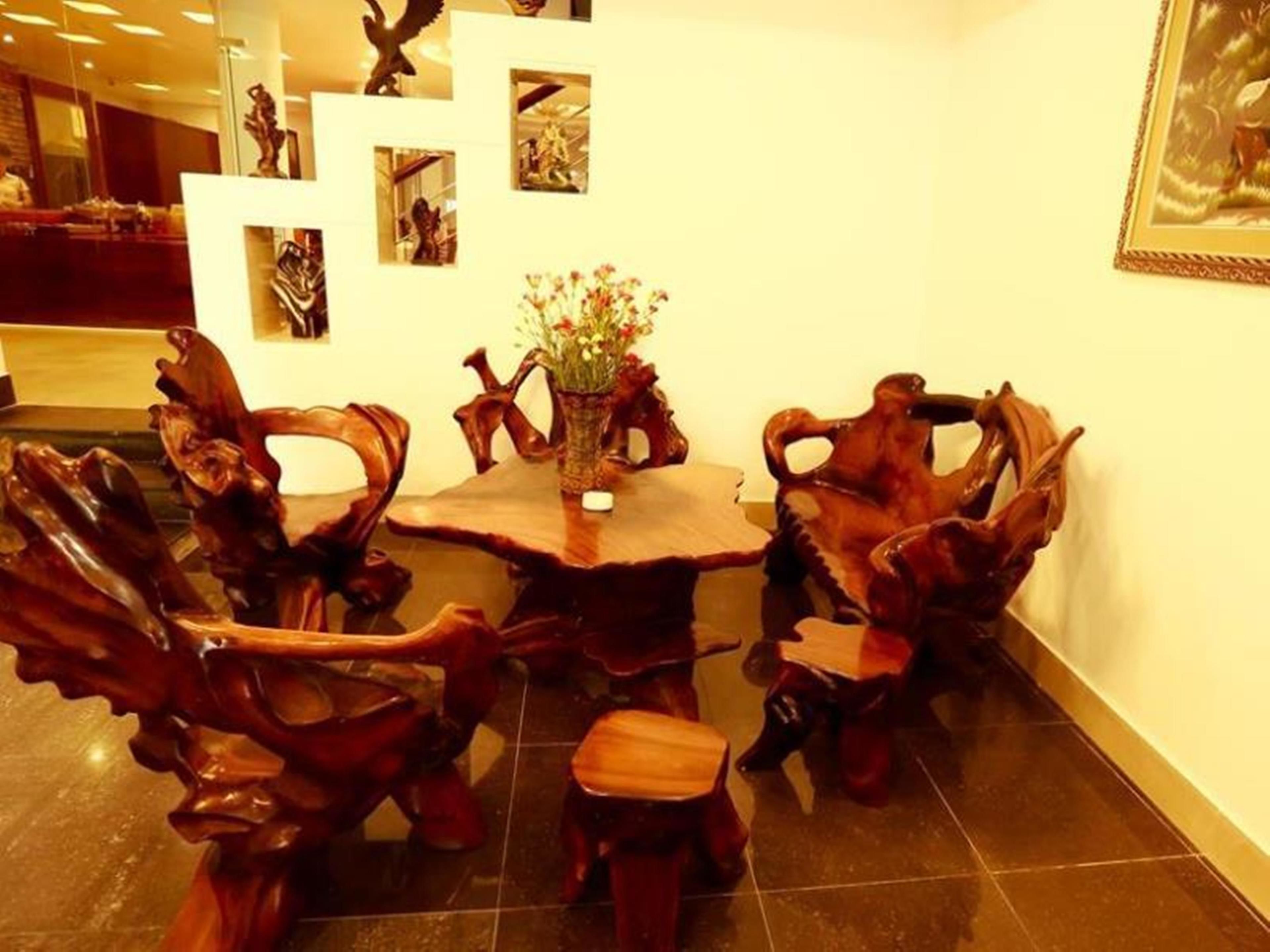 Uma área de refeições com uma mesa redonda de madeira, rodeada por cadeiras de madeira com entalhes detalhados.