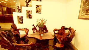 A dining area with a round wooden table surrounded by intricately carved wooden chairs. - Xuan Hung Hotel (Da Nang)