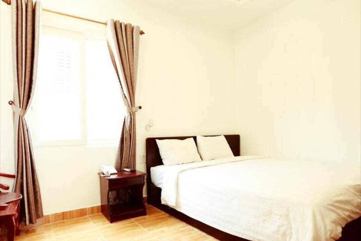 A bedroom with a bed, a nightstand, a chair, and curtains.