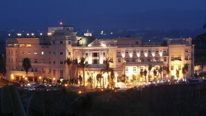 A multi-story hotel with a central courtyard, palm trees, and a fountain. - Le Beau Max Resort (Fanlu)