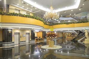A spacious lobby with a central floral arrangement, multiple floors, and a grand staircase. - Le Beau Max Resort (Fanlu)