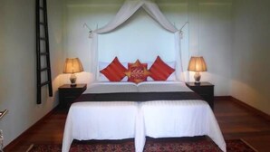 A bedroom with a bed under a canopy, two bedside tables with lamps, and a wooden floor. - Panji Panji Tropical Wooden Home (Langkawi)