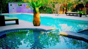 A swimming pool with a tiled edge, a bench, and a potted plant in the center. - Panji Panji Tropical Wooden Home (Langkawi)
