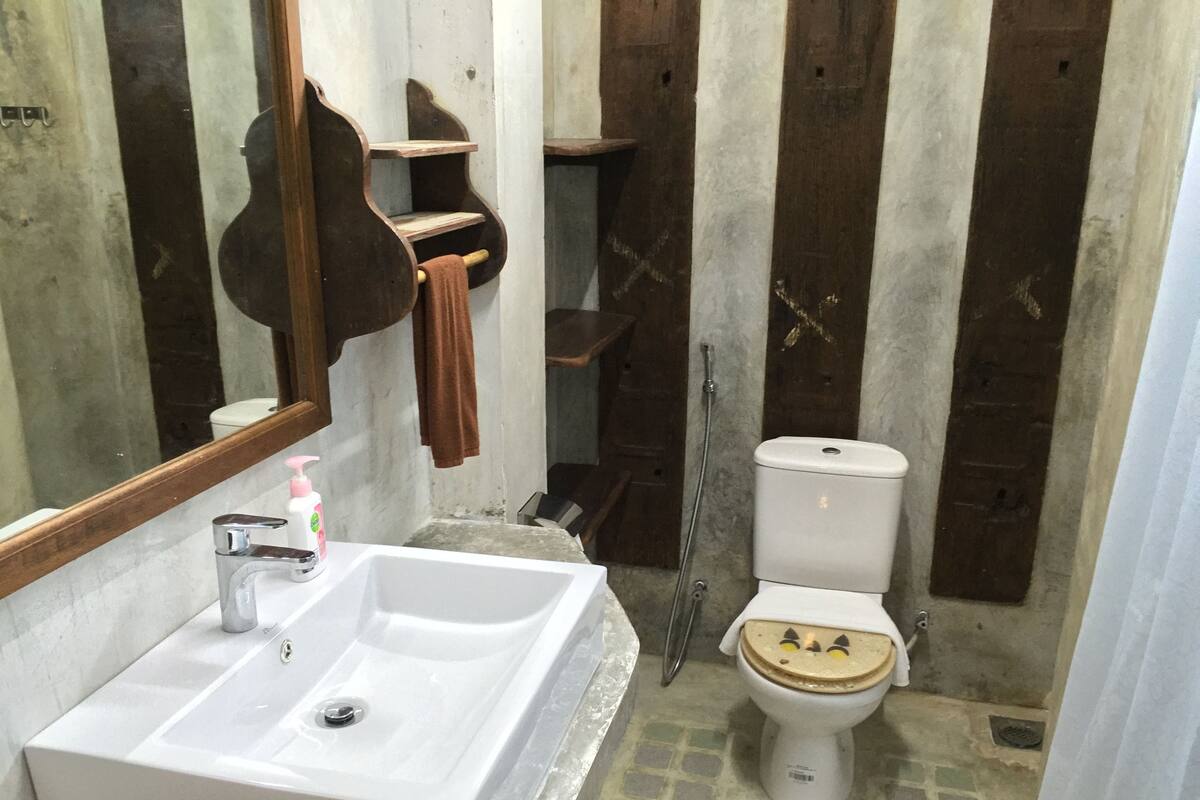 A bathroom with a white sink, a mirror, a toilet, and a shower area.