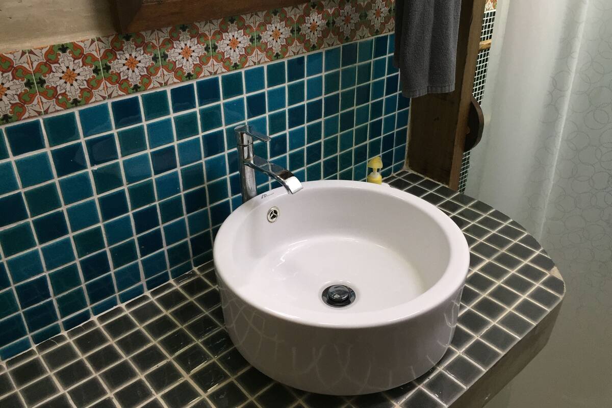 A bathroom with a white sink, blue and black patterned tiles, and a mirror above the sink.