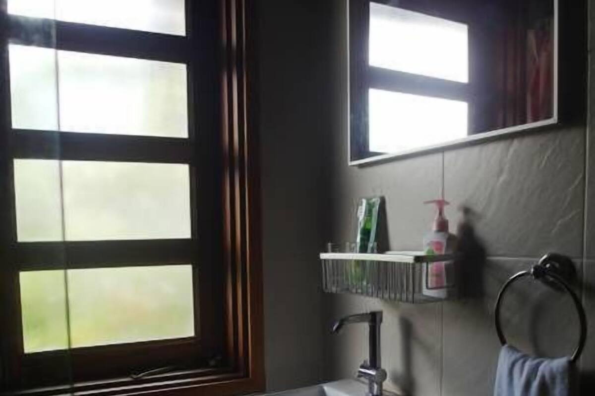 A bathroom with a window, a sink, a mirror, and a towel rack.