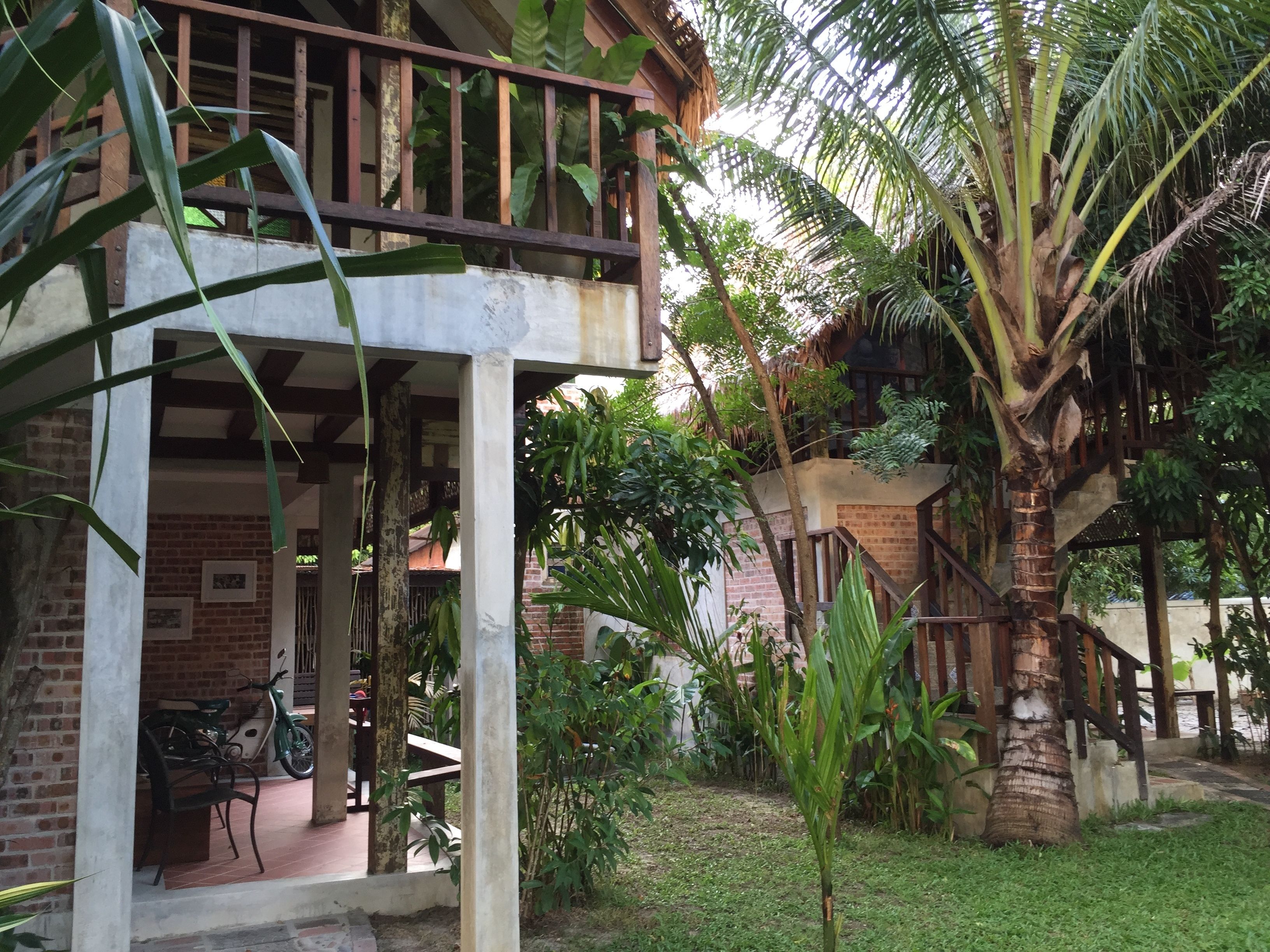 A covered outdoor area with a brick wall, a wooden railing, and a palm tree.