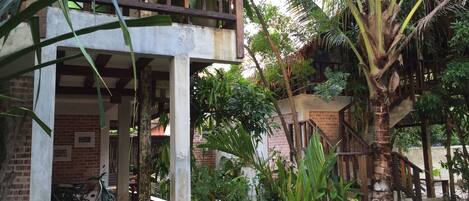 A covered outdoor area with a brick wall, a wooden railing, and a palm tree.