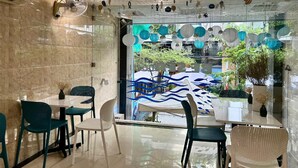 A restaurant with a modern interior, marble walls, and a view of a garden through a glass wall. - BeSea Hotel Da Nang (Da Nang)