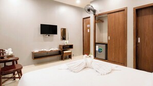 A hotel room with a bed, a TV, a wooden wardrobe, a mirror, a desk with a chair, and a minibar. - BeSea Hotel Da Nang (Da Nang)