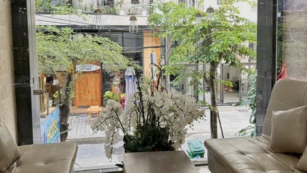 A modern interior with a sofa, a wooden coffee table, and hanging pendant lights. - BeSea Hotel Da Nang (Da Nang)
