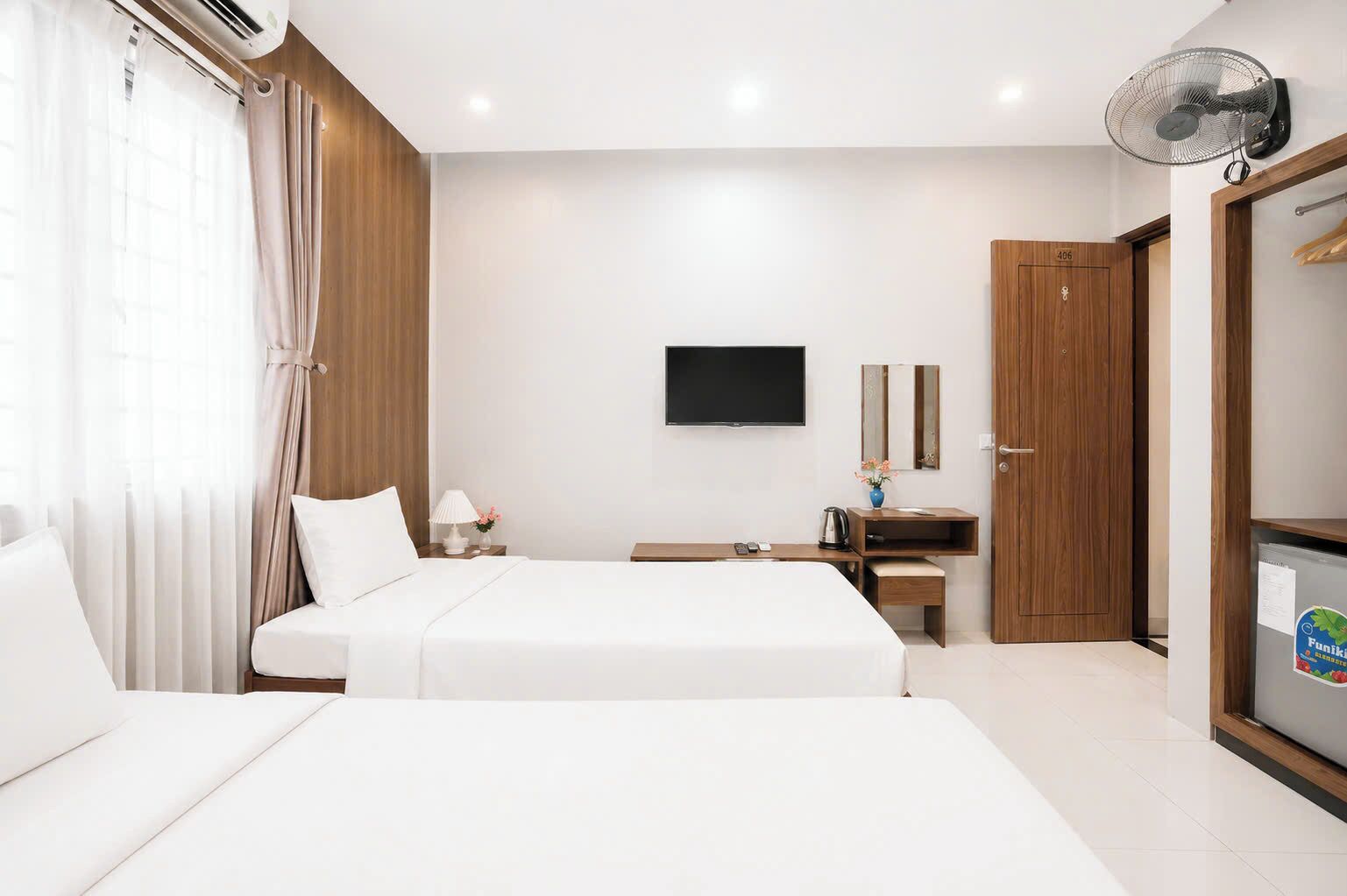 A hotel room with a bed, bedside table, TV, and a wardrobe.