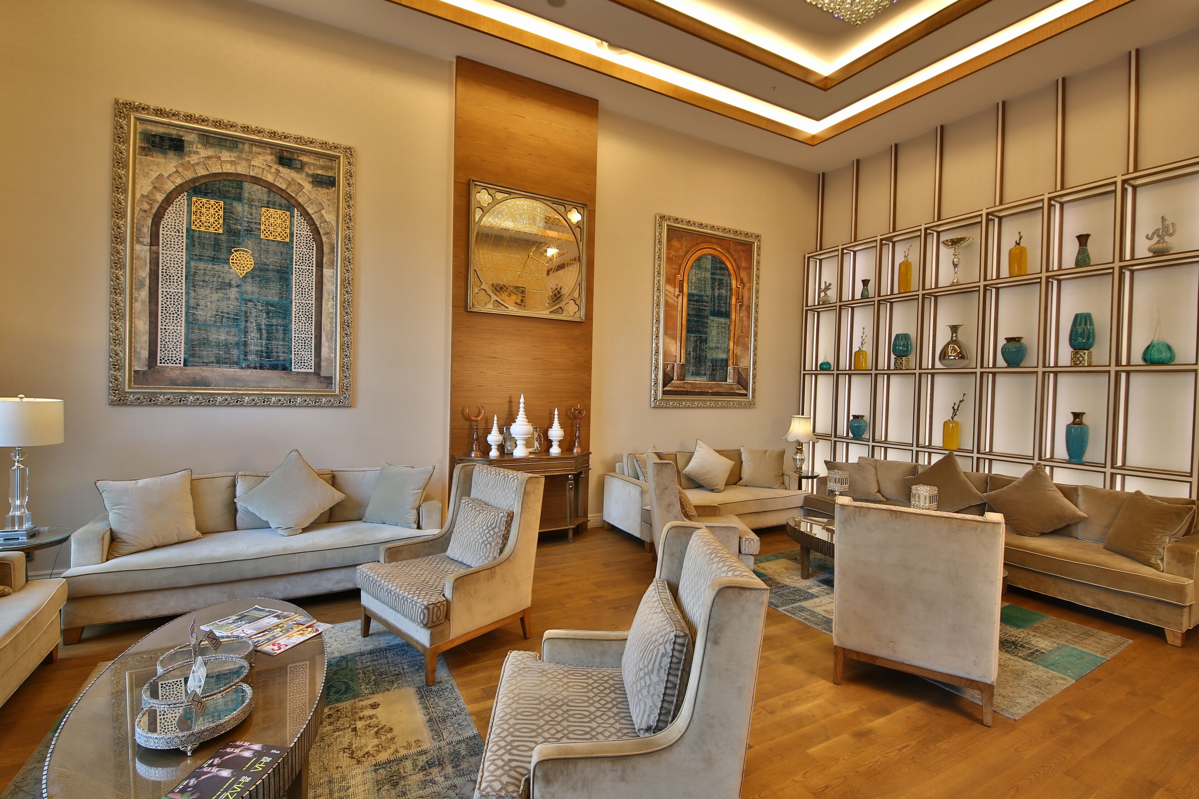 Een ruime woonkamer met een bank, fauteuils, een salontafel en decoratieve objecten.