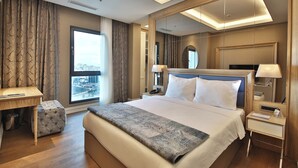 Habitación de hotel moderna con una cama grande, un escritorio y vistas a la ciudad.