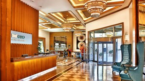 Un vestíbulo de hotel con recepción, zona de check-in, asientos y mostrador de salida.
