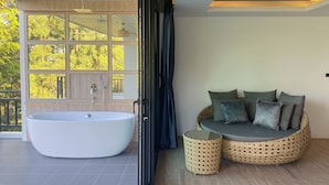 A modern bathroom with a freestanding bathtub, a wicker sofa with cushions, and a small round table. - Baan Taranya Koh Yao Yai Resort (Ko Yao)
