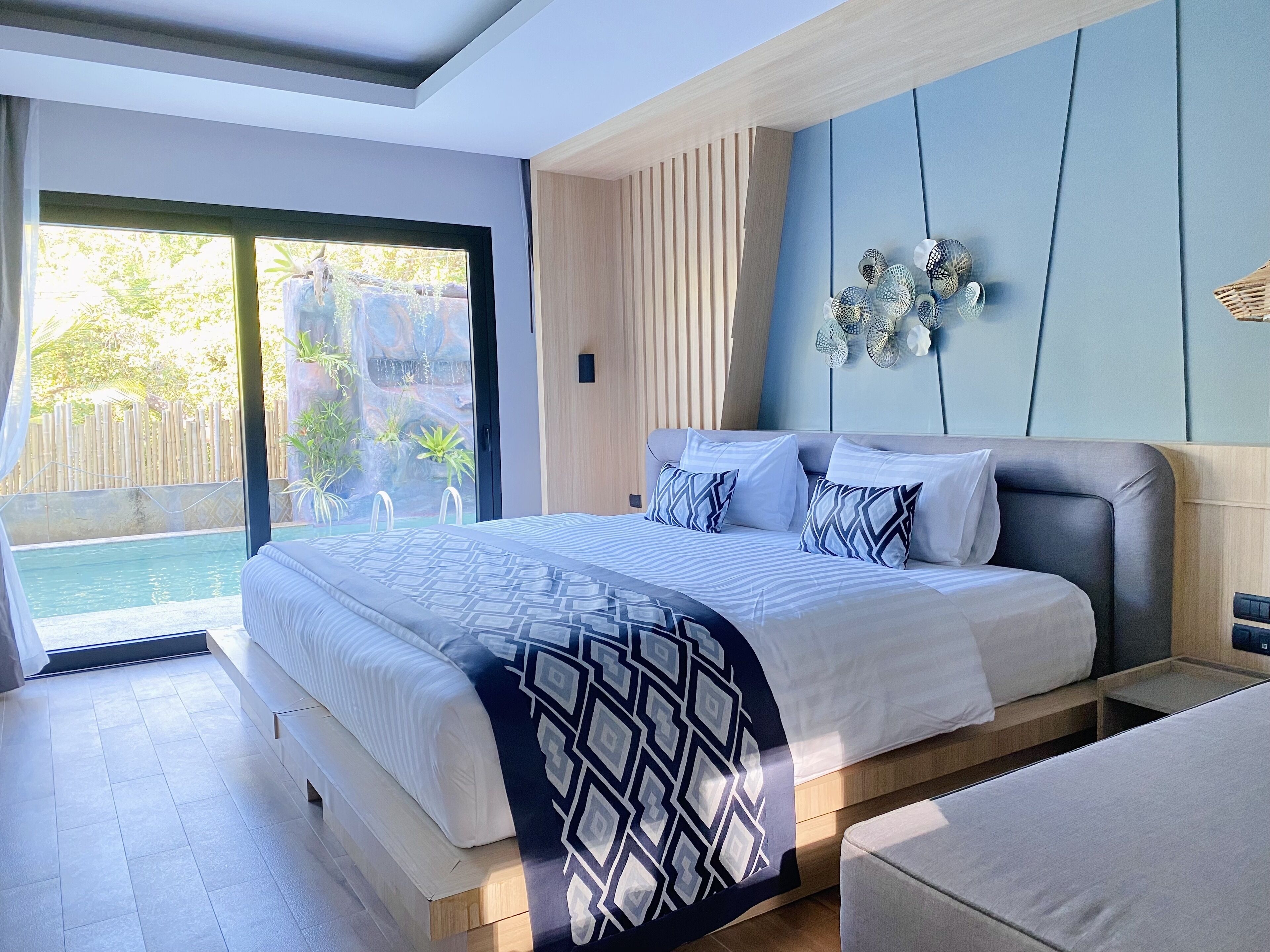 Un dormitorio moderno con una cama grande, vista a una piscina y un ventanal corredero que da a un espacio exterior.