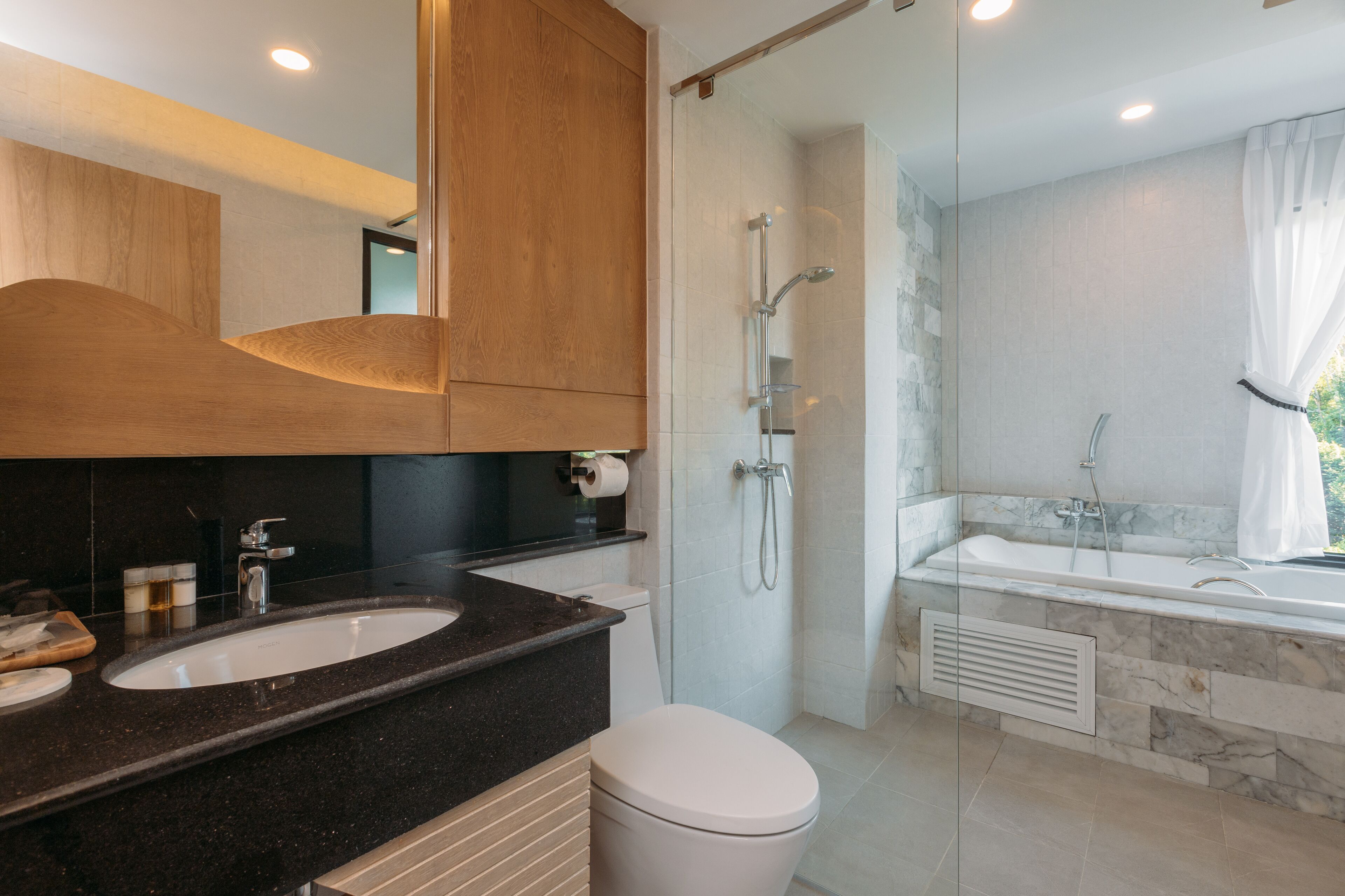 A modern bathroom with a large sink, toilet, and separate shower and bathtub area.