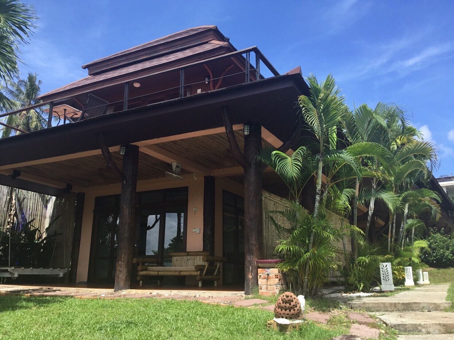 A building with a covered outdoor area, wooden pillars, and a bench.