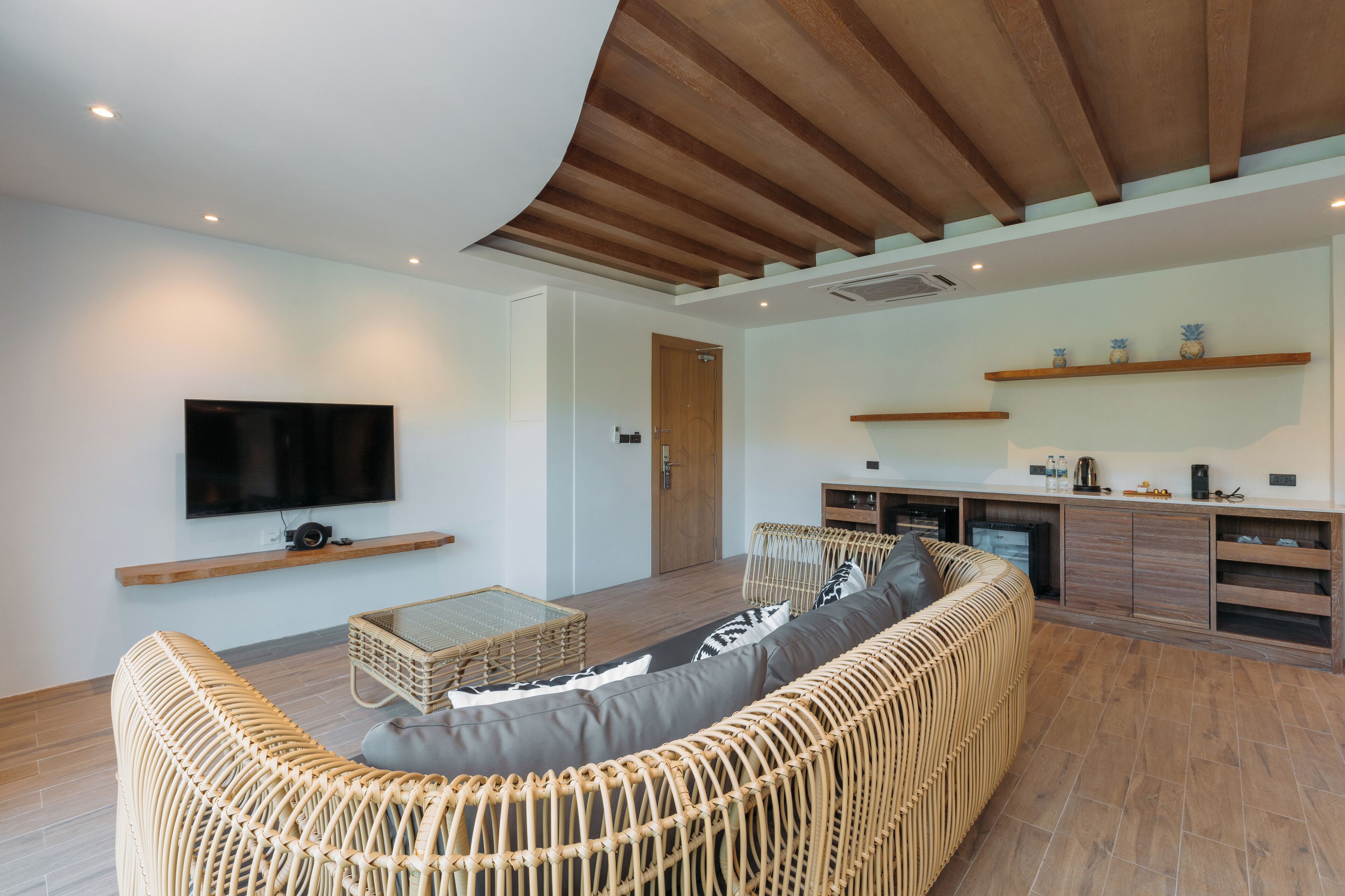 A modern living room with a curved ceiling, a large sofa, a coffee table, and a television mounted on the wall.