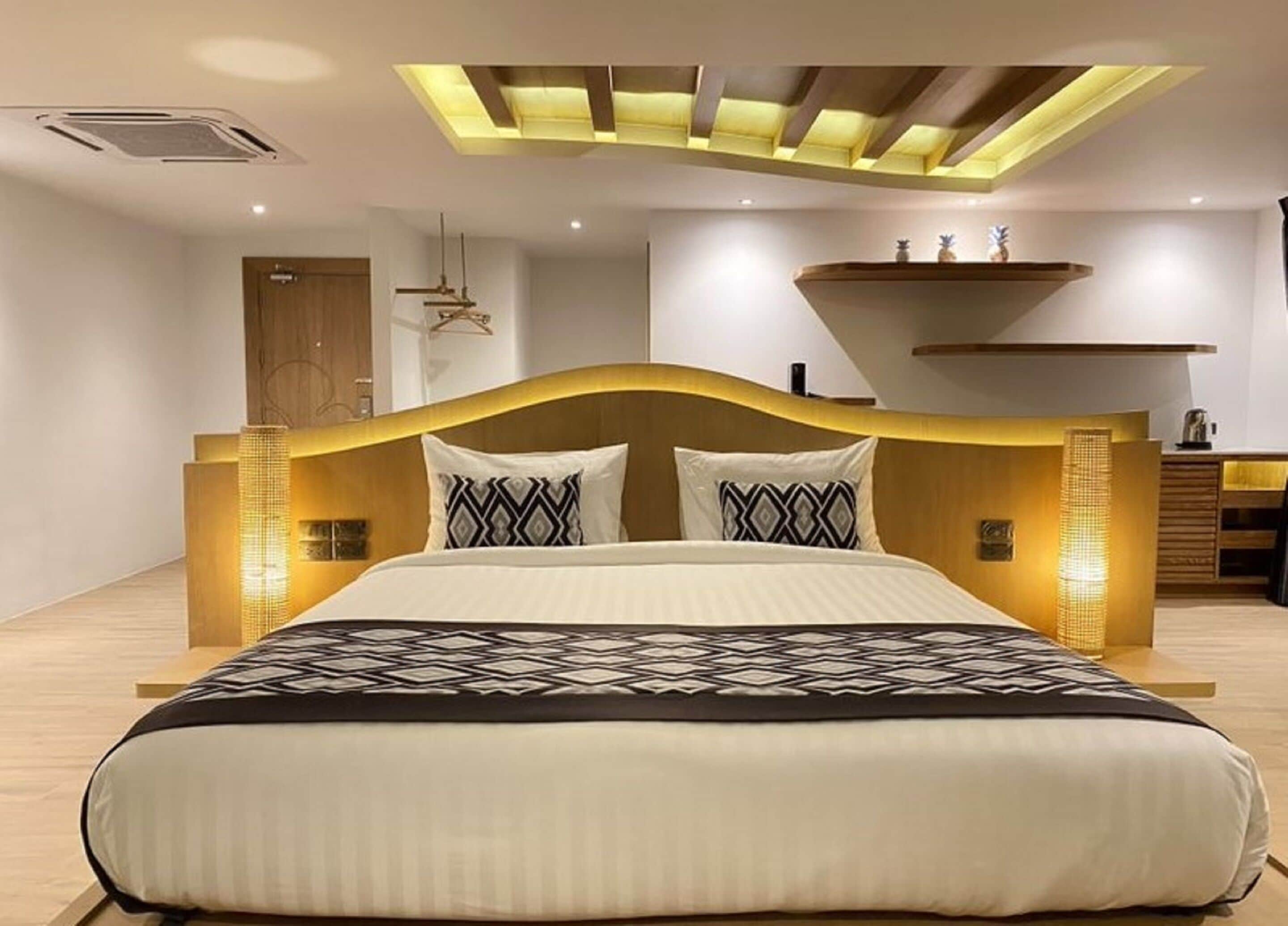 Une chambre à coucher moderne avec un grand lit, une tête de lit en bois et un éclairage intégré.