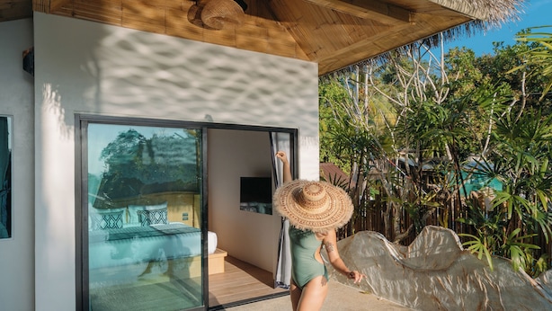 A modern house with a glass door leading to a swimming pool, surrounded by lush greenery. - Baan Taranya Koh Yao Yai Resort (Ko Yao)