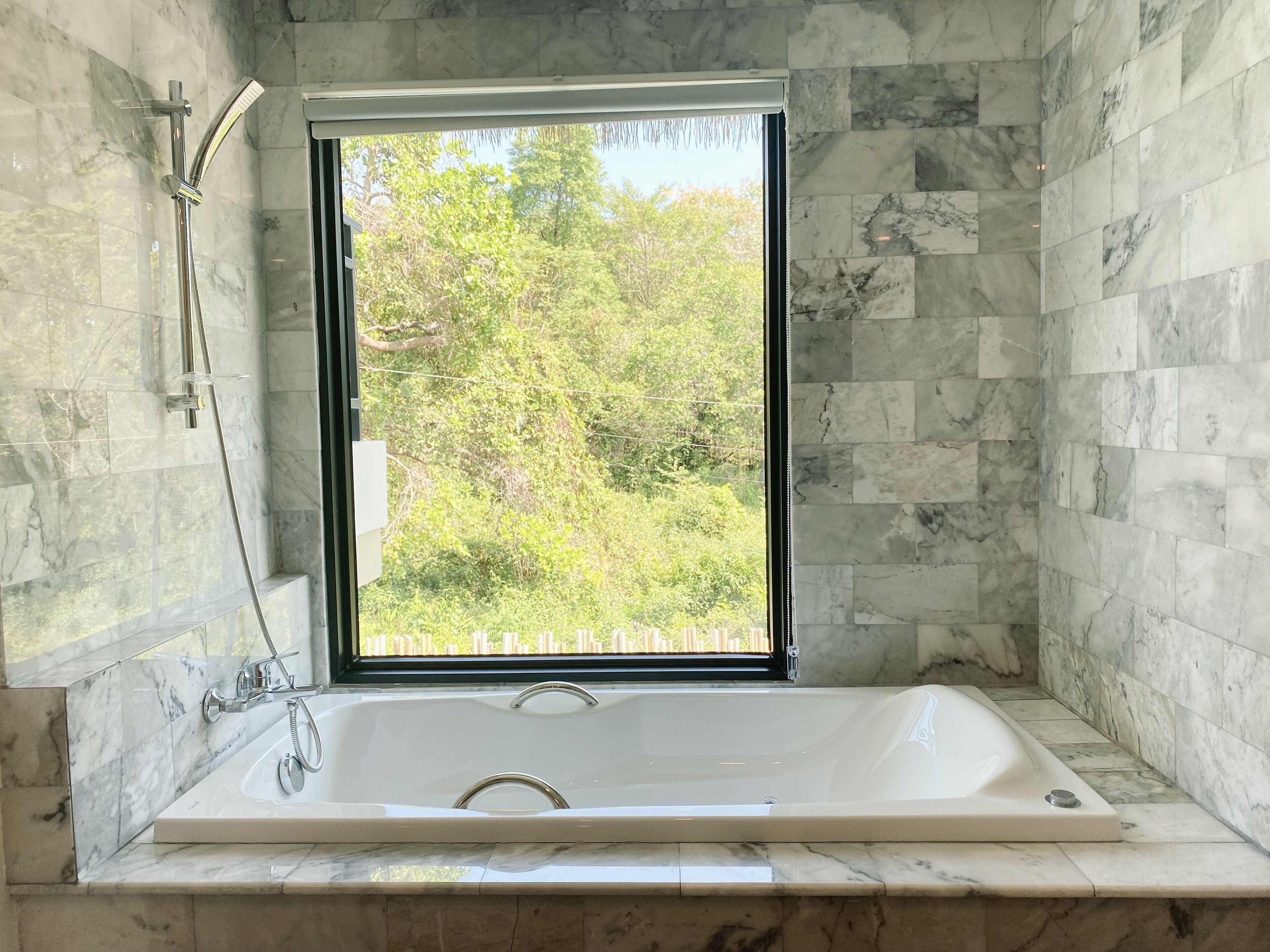 Un baño con un ventanal grande, una bañera y una ducha.