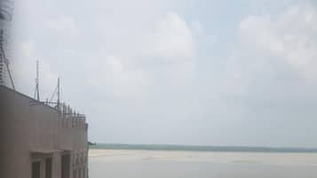 A view of a river from a building with a flat roof and a brick wall.