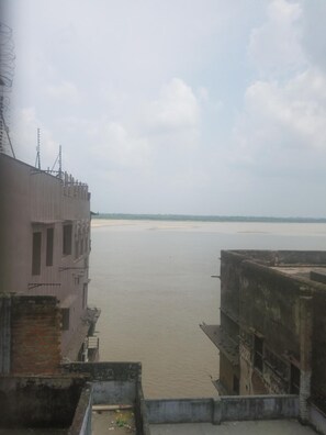 A view of a river from a building with a flat roof and a brick wall. - Baba Guest House (Varanasi)