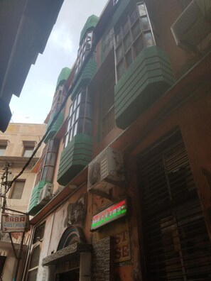 A multi-story building with balconies, a sign for "Baba Guest House," and a neon sign advertising "Baba's Restaurant." - Baba Guest House (Varanasi)