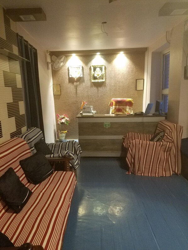 A reception area with striped sofas, a reception desk, and wall-mounted lights. - Baba Guest House (Varanasi)