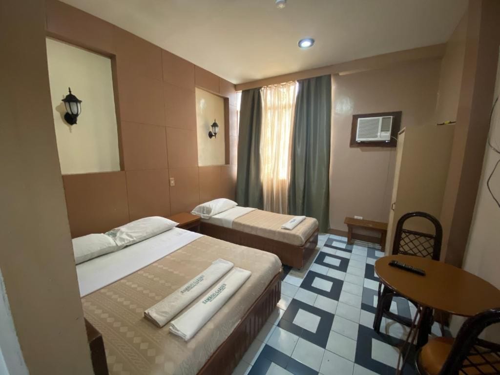Una camera d'albergo con due letti, un tavolino, una sedia e un televisore.