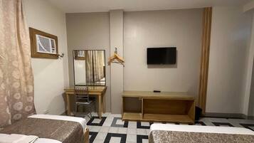 Een hotelkamer met twee bedden, een bureau, een stoel, een televisie en een spiegel.