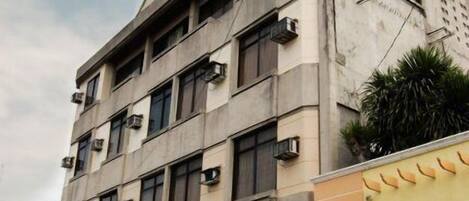 Un edificio de varios pisos con un camión de reparto estacionado adelante.