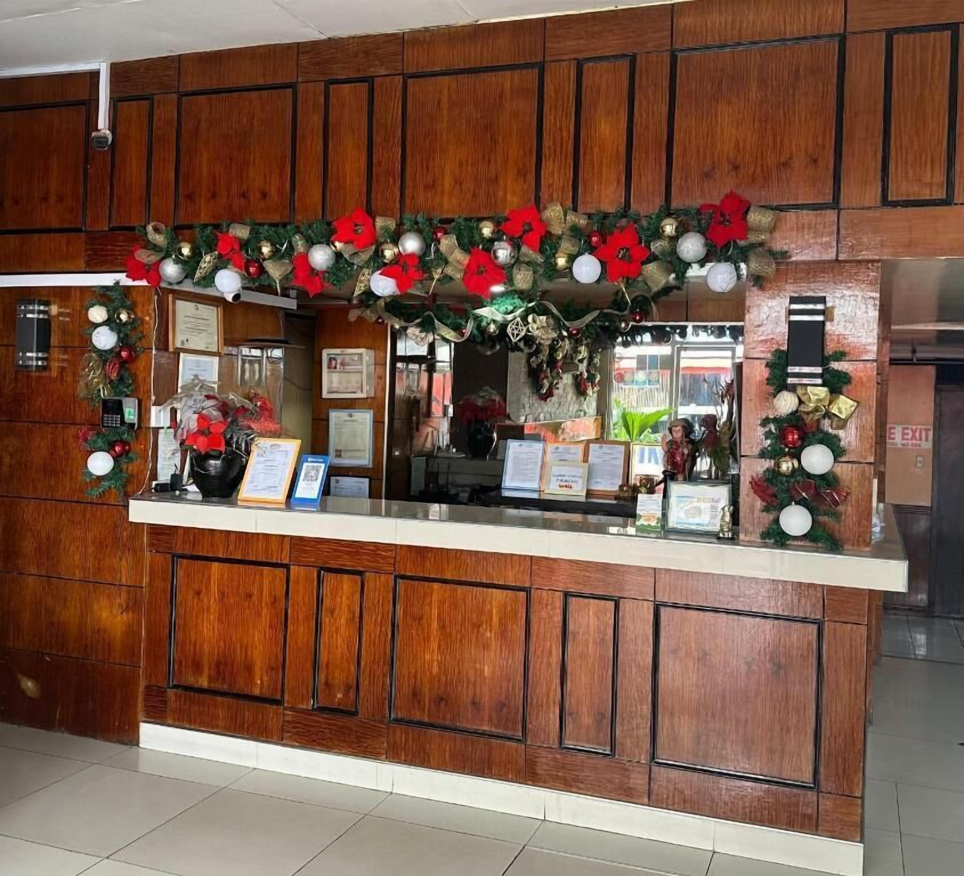 A reception desk with a wooden panel design, a counter, and Christmas decorations including poinsettias and ornaments.