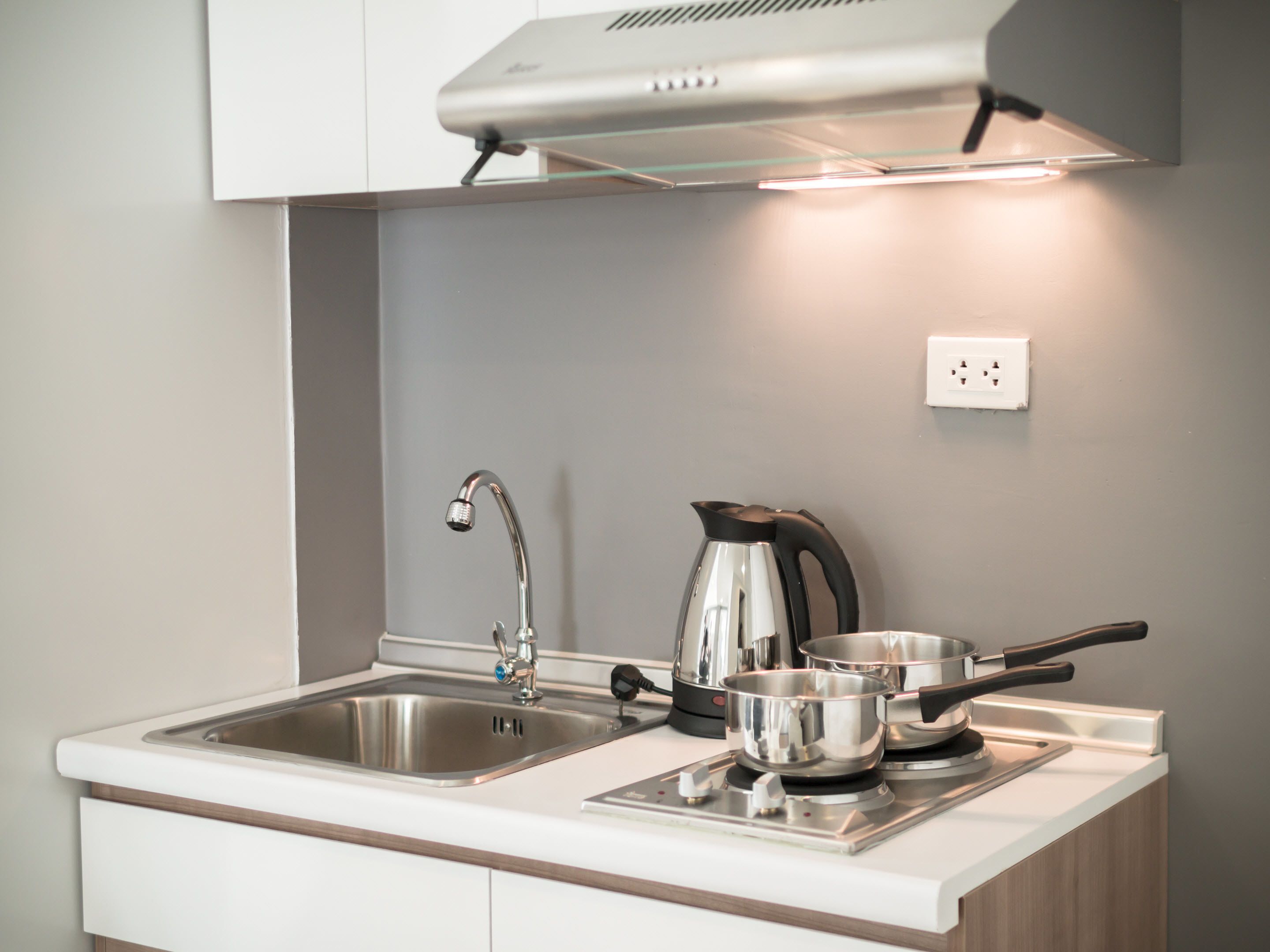 Una cocina moderna con un lavamanos de acero inoxidable, una tetera y una estufa.