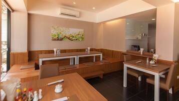Un restaurante moderno con mesas y bancos de madera, un equipo de aire acondicionado y un cuadro en la pared.
