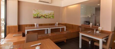 A modern restaurant with wooden tables and benches, an air conditioning unit, and a painting on the wall.