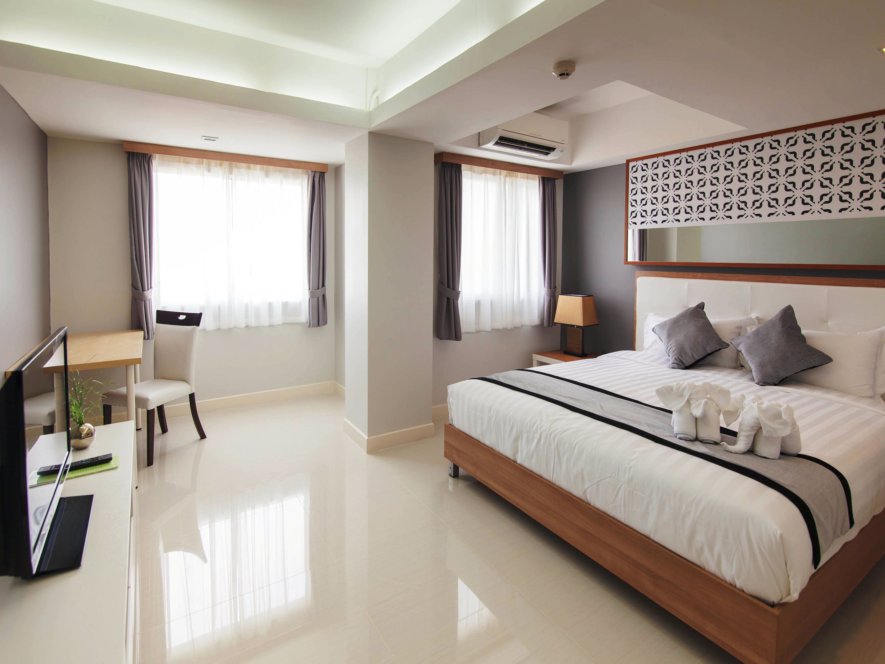 Une chambre d’hôtel moderne avec un grand lit, un bureau et une chaise.