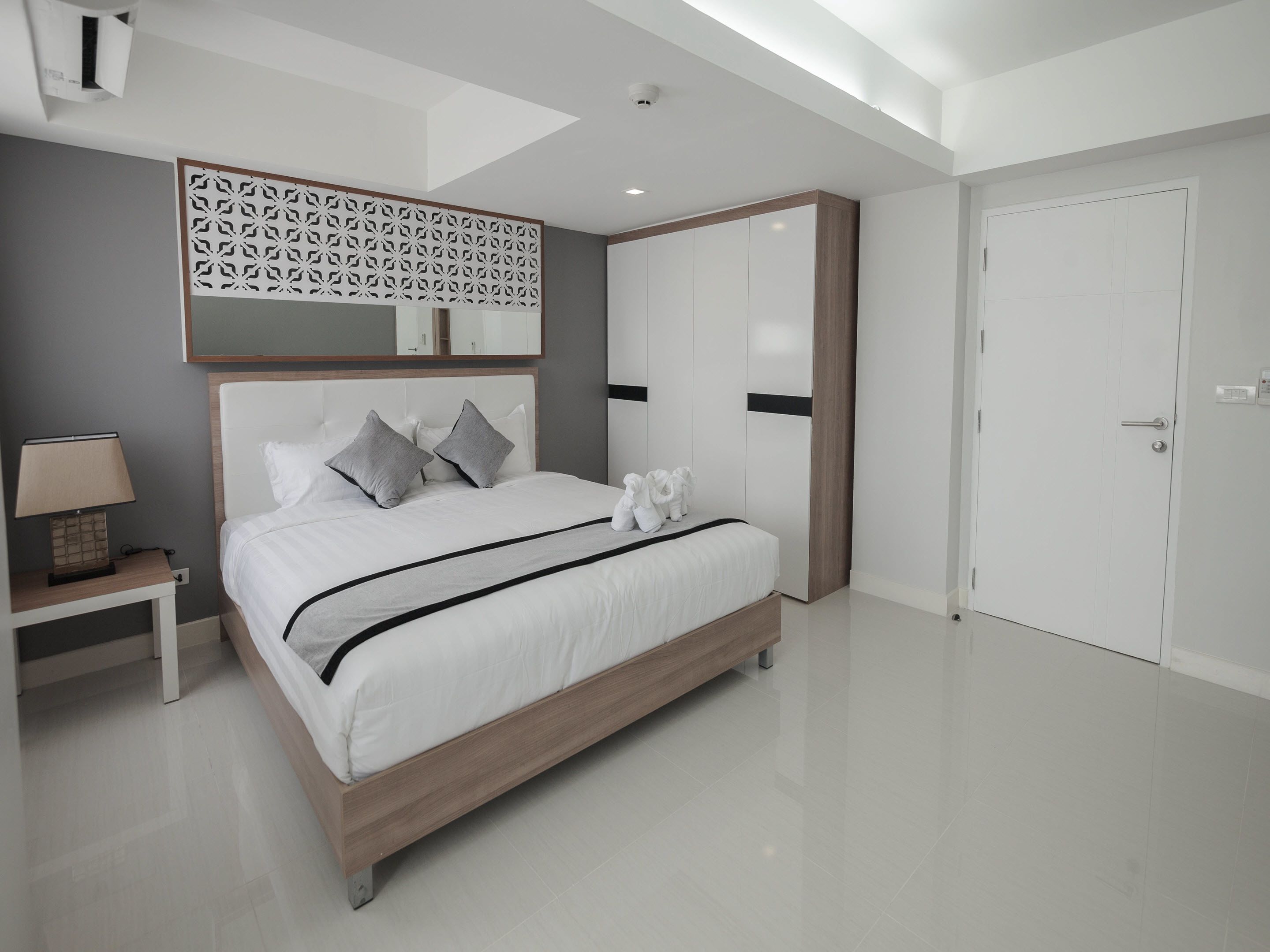 Un dormitorio moderno con una cama grande, una mesita de noche, un armario y un panel decorativo en la pared.