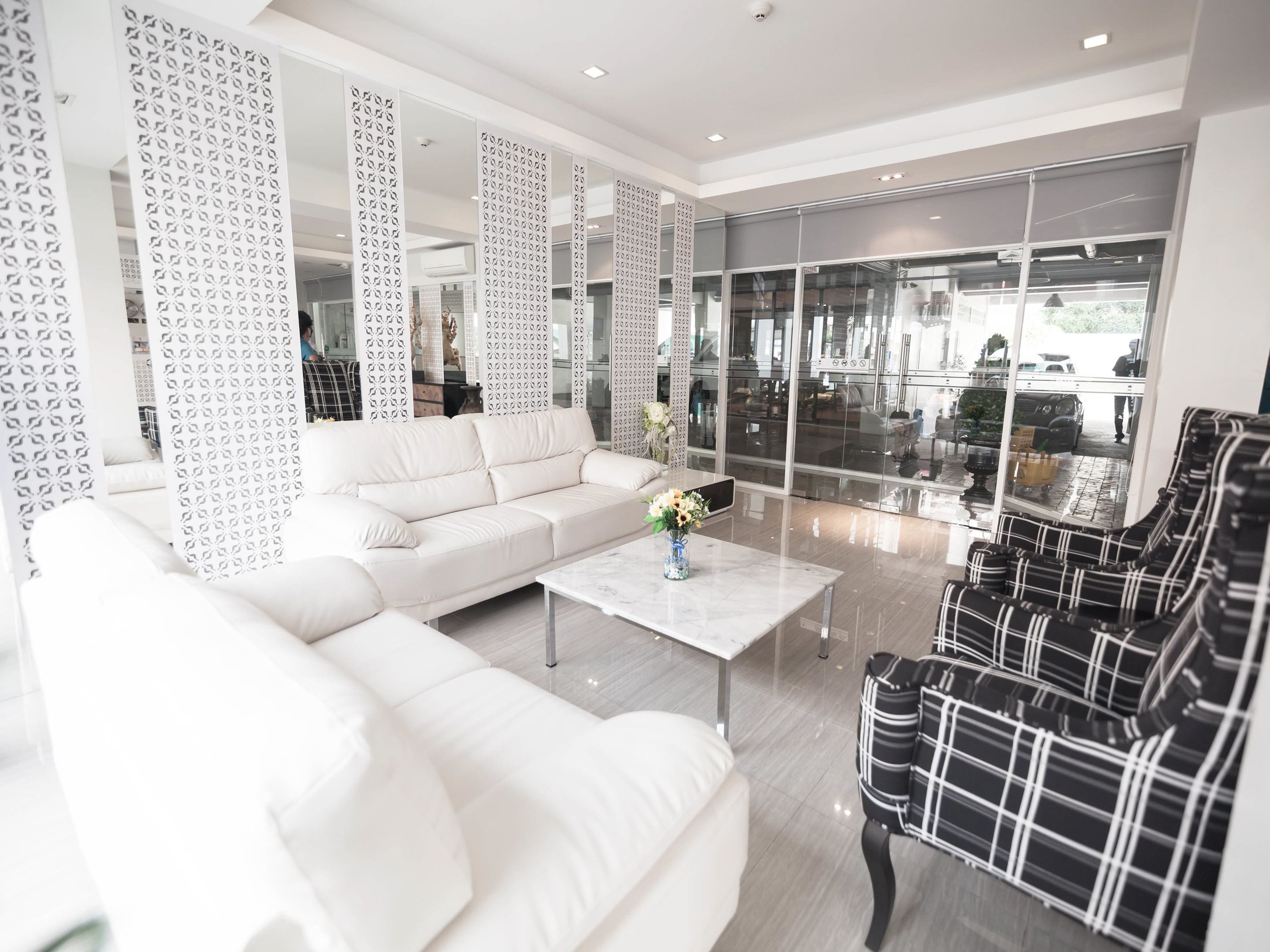 A modern hotel lobby with a white sofa, a coffee table with a vase, and a black and white patterned chair.