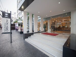 A hotel entrance with a red carpet, steps leading up to the door, and a signboard advertising the hotel.
