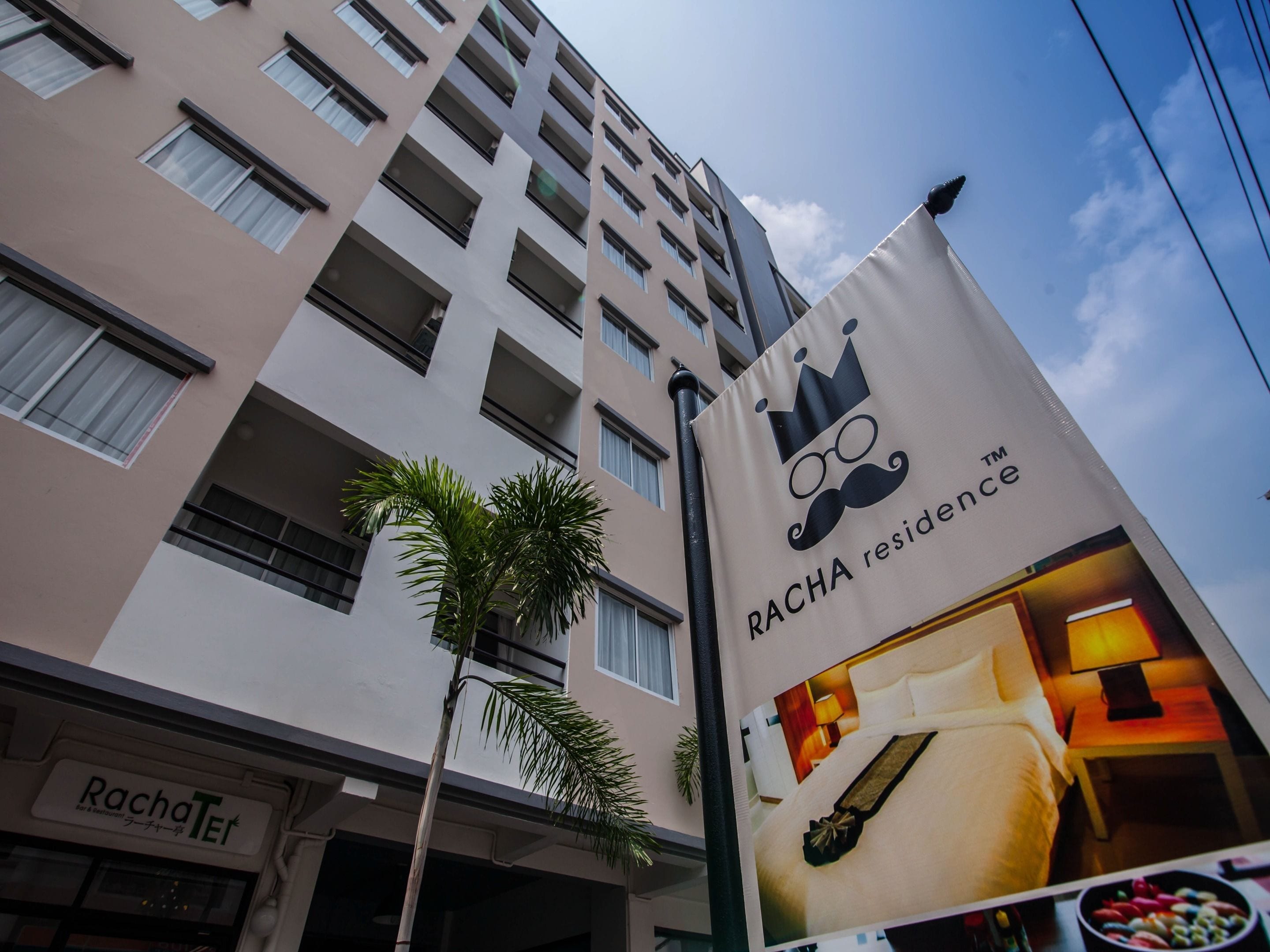 Un edificio de hotel con un cartel que anuncia Racha Residence.