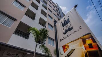 A hotel building with a banner advertising Racha Residence.