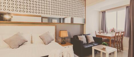 Una habitación de hotel moderna con una cama grande, un sofá de cuero negro, una mesa de comedor con sillas y un panel decorativo en la pared.