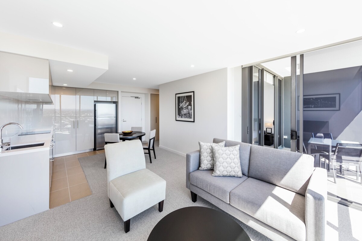 A modern living space with a kitchen, dining area, and a balcony with a city view.