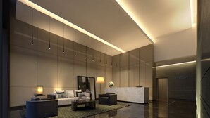 A modern lobby with a reception desk, seating area, and a large mirror.