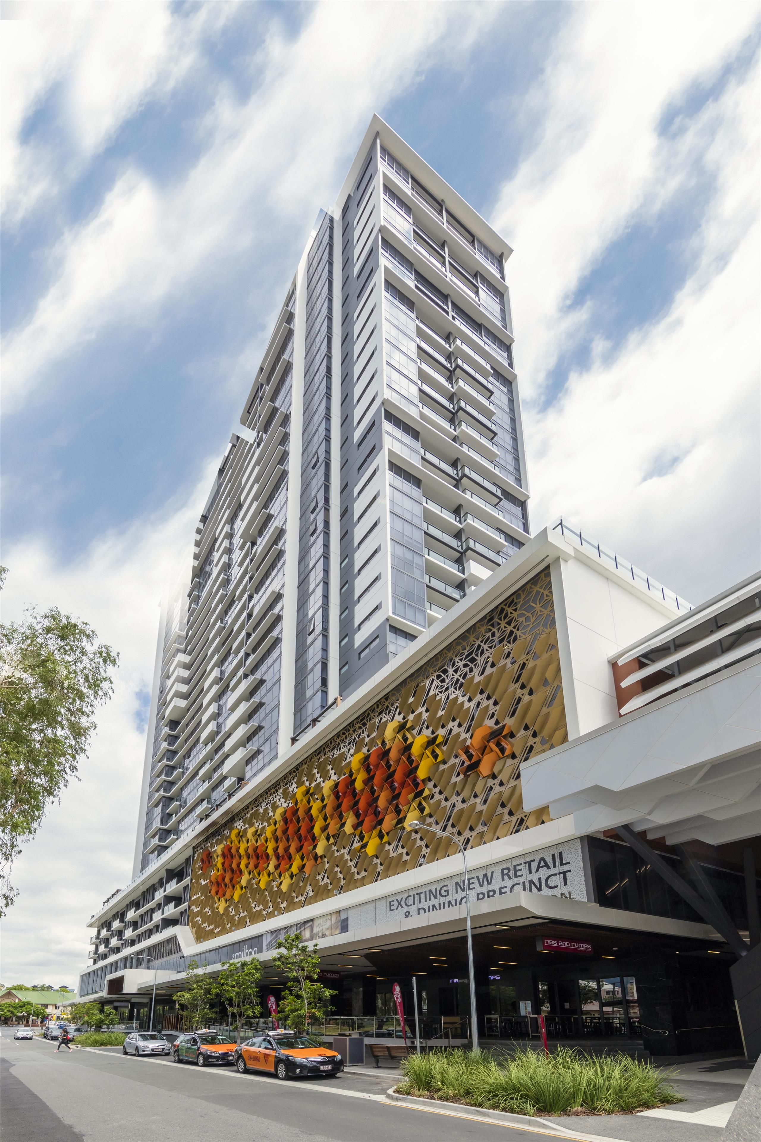 Un moderno edificio de gran altura con una fachada distintiva que presenta un diseño geométrico.