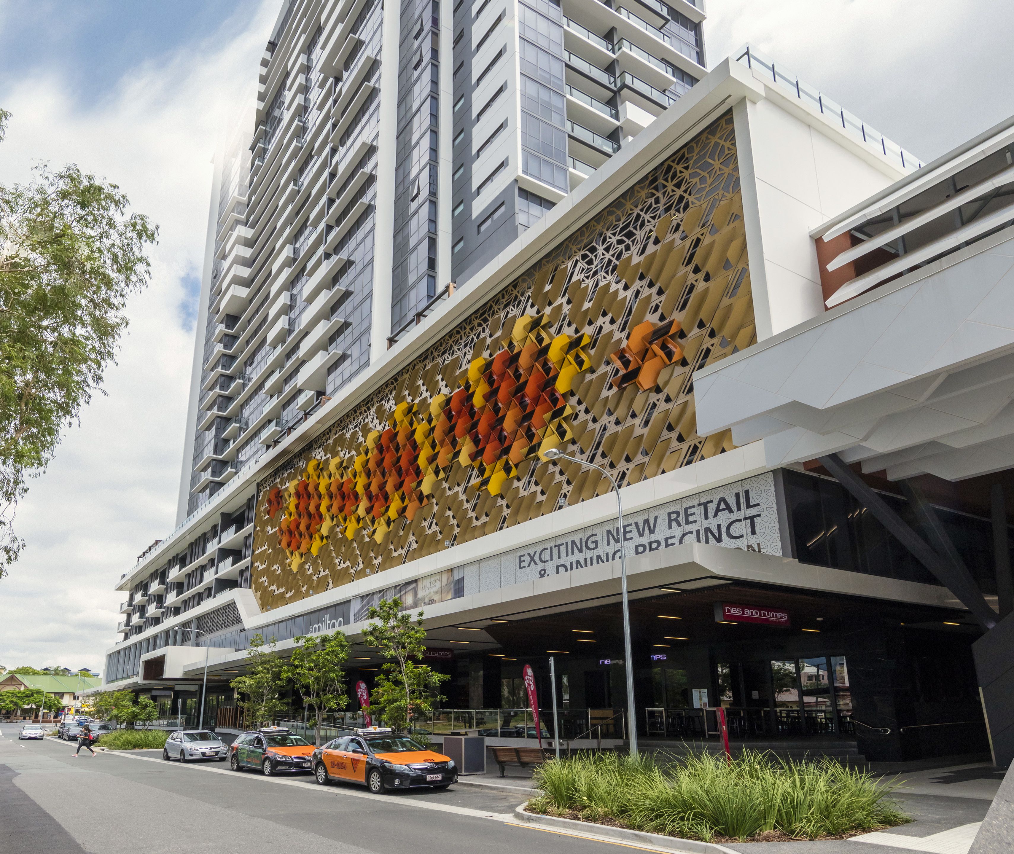 A modern building with a large billboard advertising a new retail precinct.